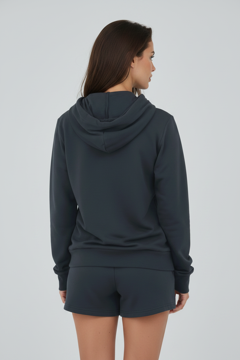 A woman shown from the back wearing a dark charcoal gray hooded sweatshirt and matching shorts against a light gray studio background.