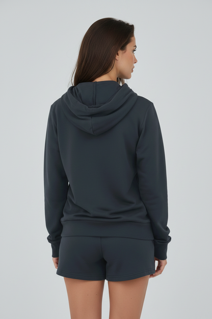 A woman shown from the back wearing a dark charcoal gray hooded sweatshirt and matching shorts against a light gray studio background.
